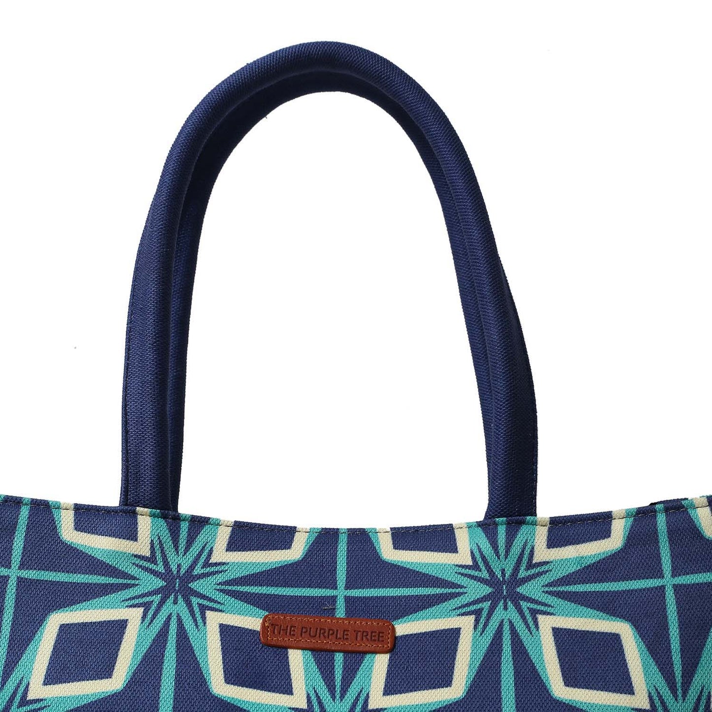 A stylish tote bag with a blue and green pattern, accompanied by a book and another book.