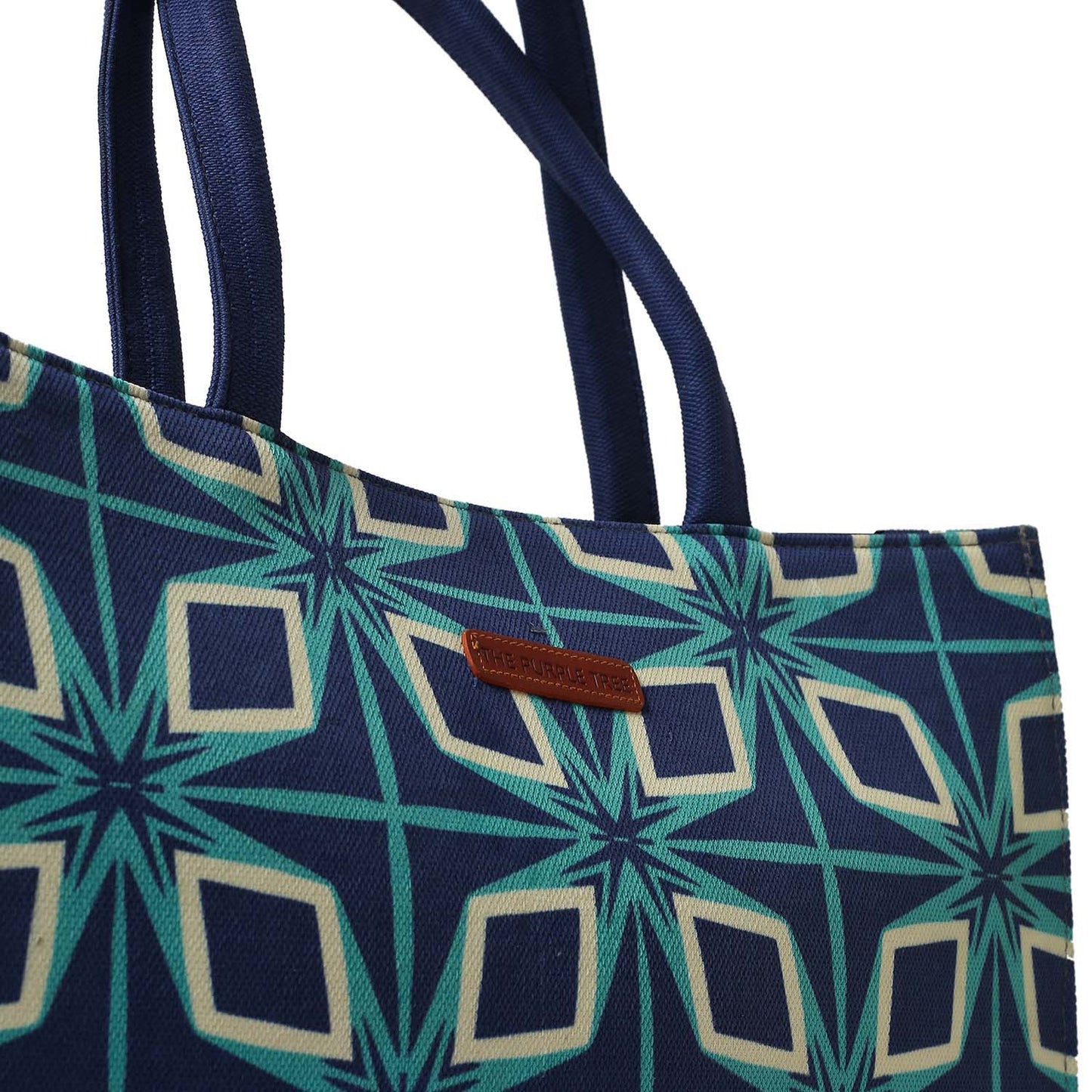  A vibrant tote bag featuring a blue and green pattern, alongside two books.