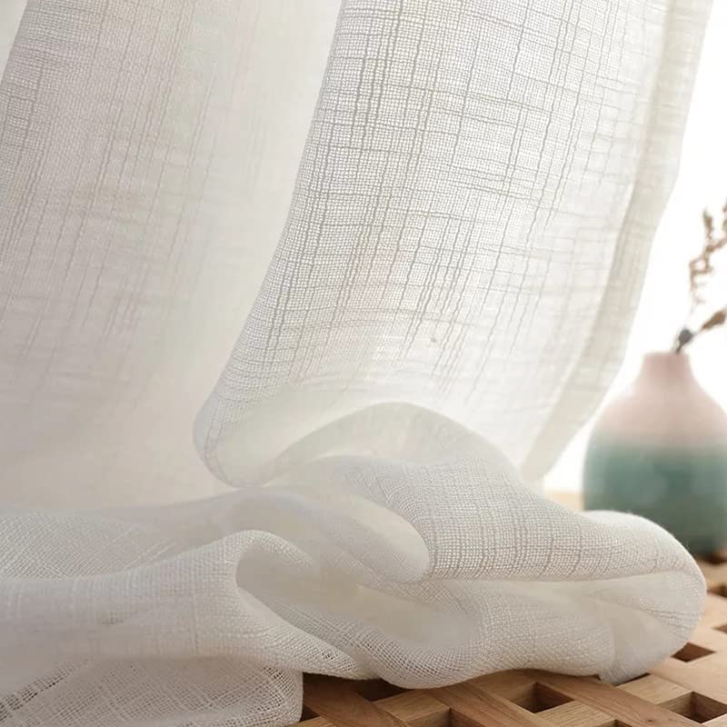 White linen curtains neatly folded on a wooden table.