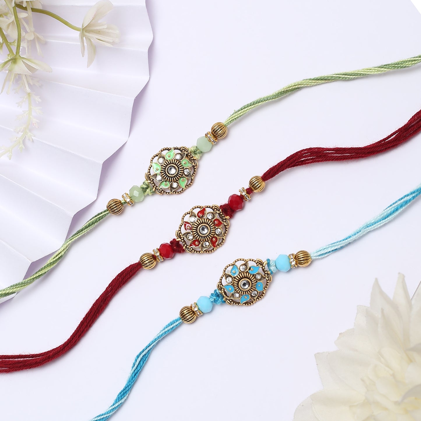 Three colorful rakhi's with gold and green beads, perfect for celebrating the bond between siblings.