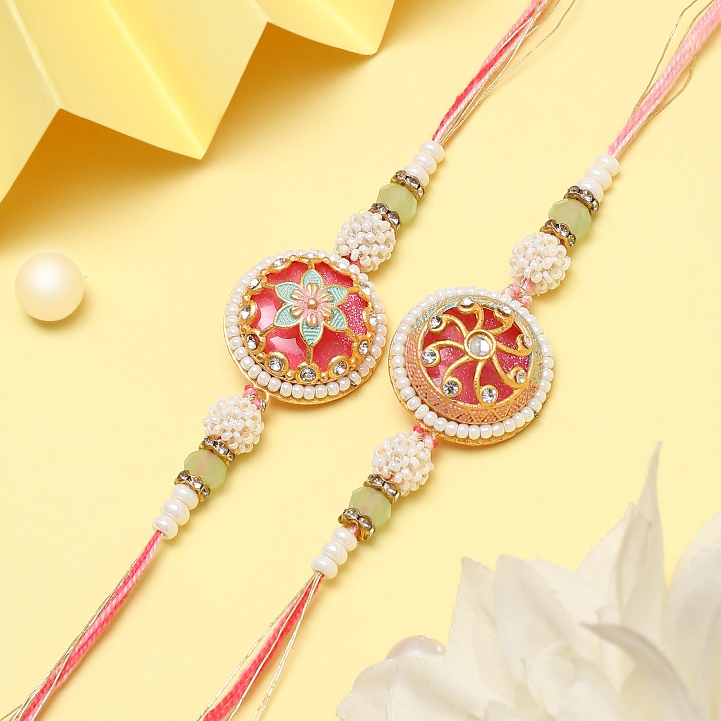 Two traditional rakhi's with pearls and beads on a yellow base.