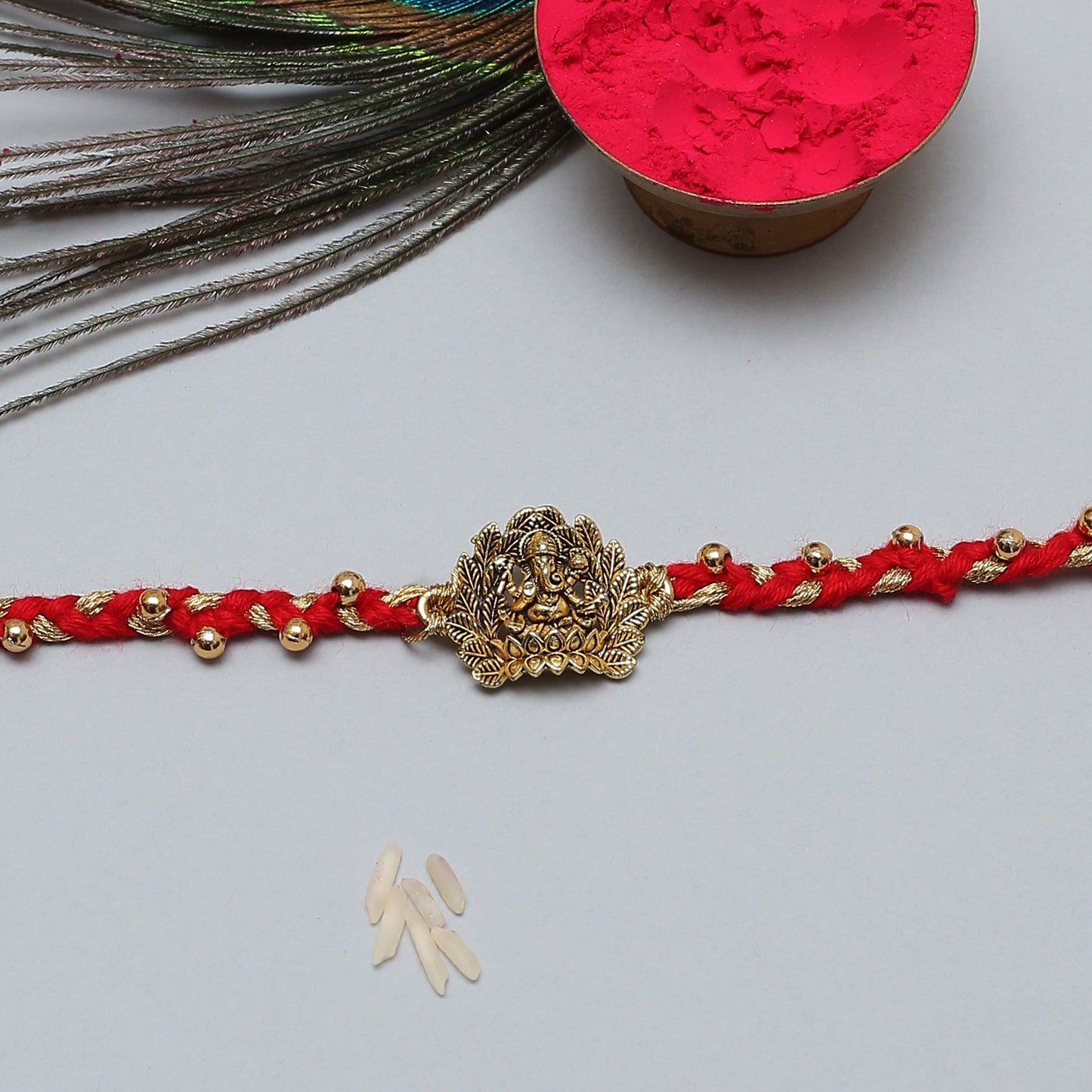  Red string Rakhi with gold charm, symbolizing good luck and protection.