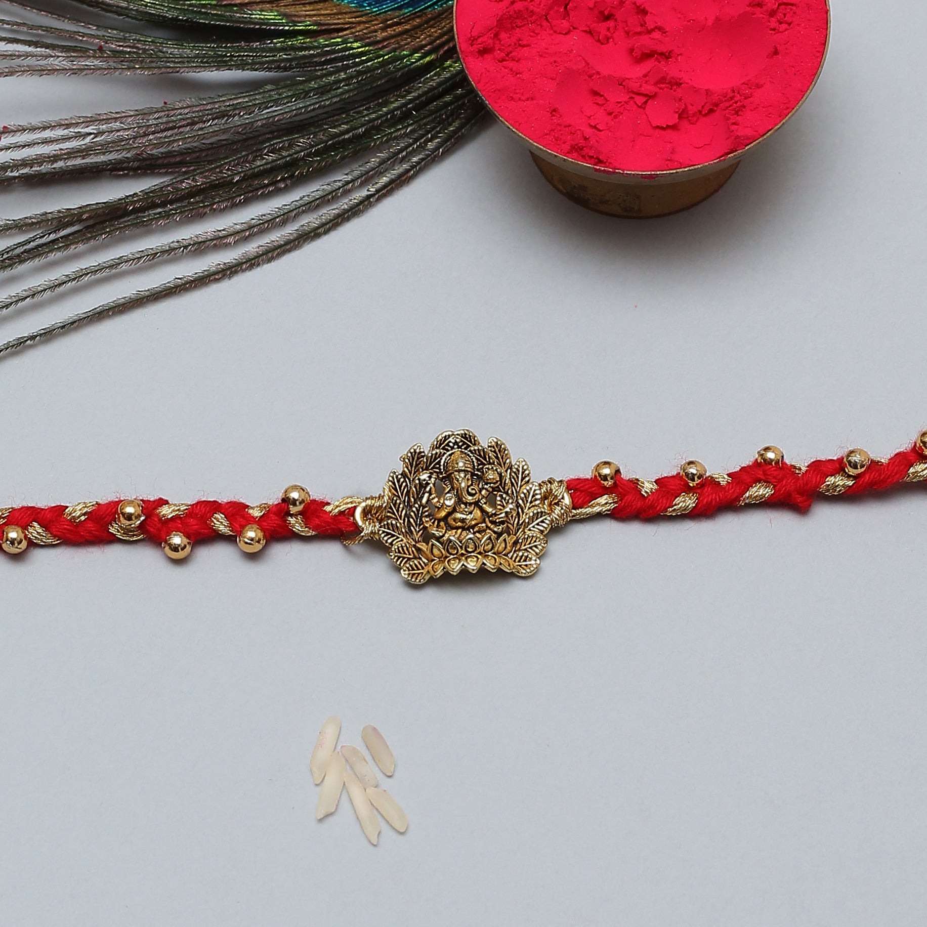  Red string Rakhi with gold charm, symbolizing good luck and protection.