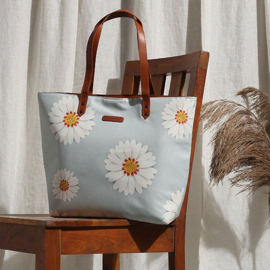  A stylish tote bag with white daisies, perfect for carrying your essentials on a sunny day out.