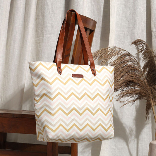 A stylish tote bag with a pink and gold chevron pattern, perfect for adding a touch of elegance to any outfit.