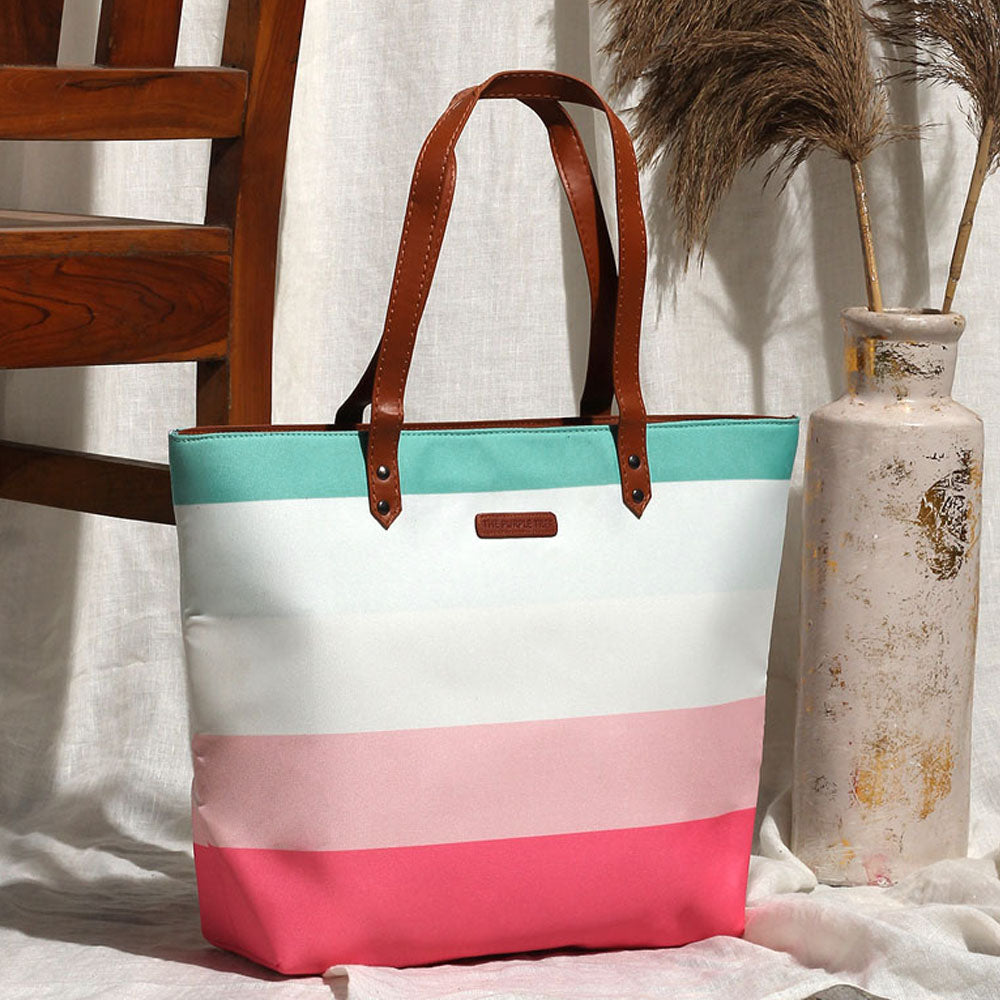 A stylish tote bag with pink, blue, and white stripes, perfect for carrying essentials on a sunny day out.