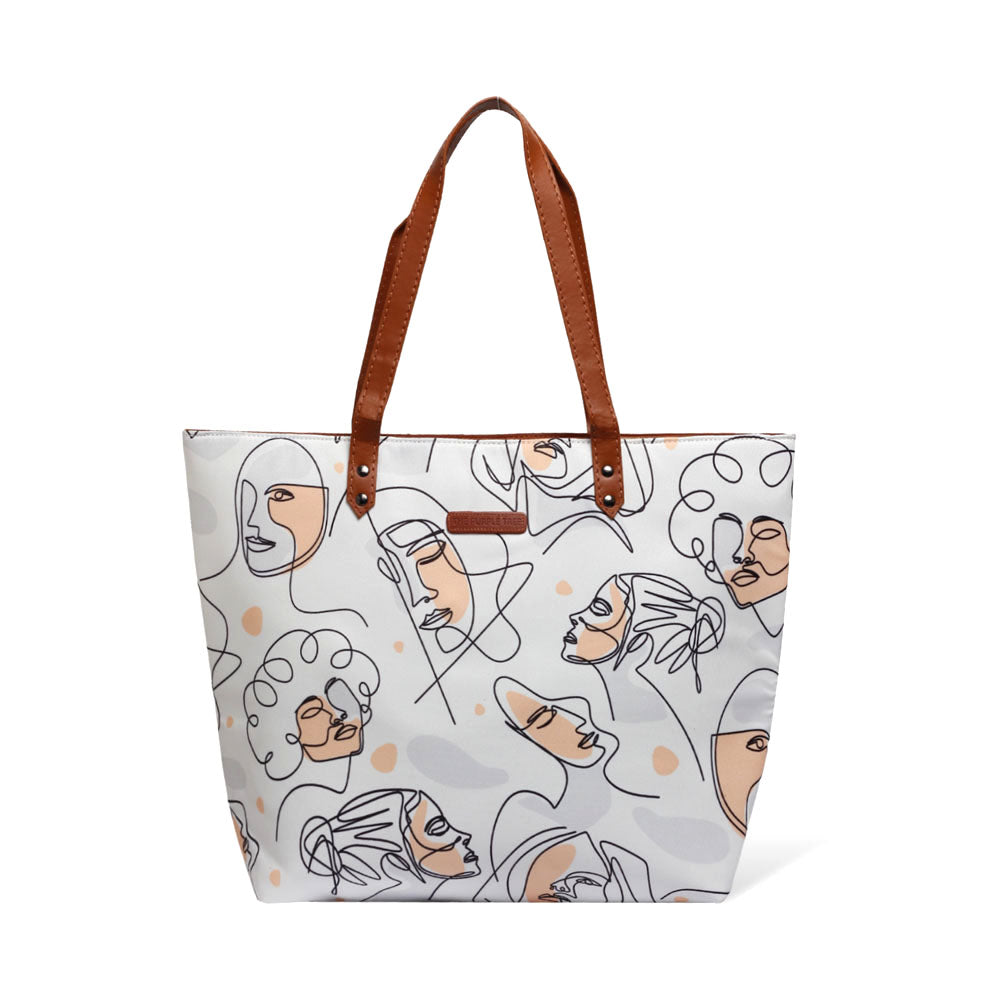 White tote bag with pattern of women's faces, perfect for carrying essentials in style.