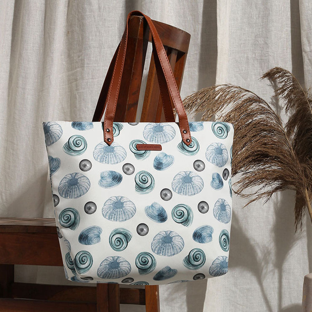 White and blue tote bag with seashells pattern, perfect for a beach day.