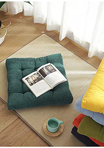 A green square cushion with a book on it.