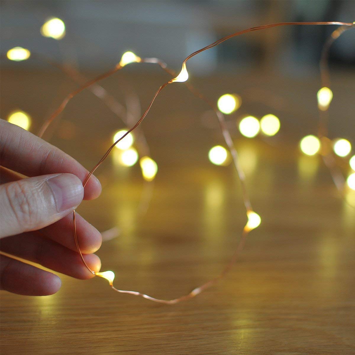 A person placing string lights on a table.