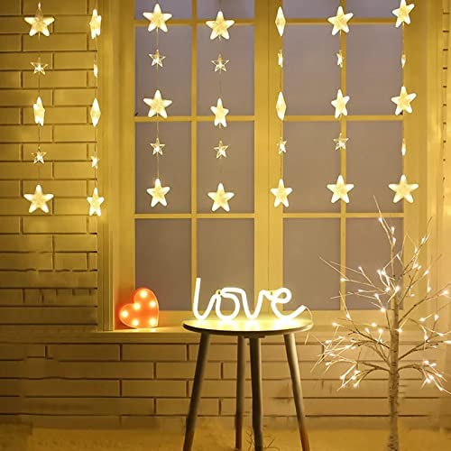 A window with a star sign and twinkling lights shining through at night.