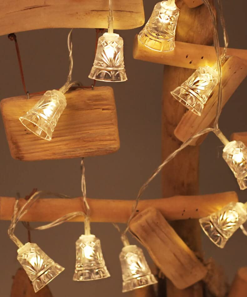  Festive lights and bells hanging from a tree branch.