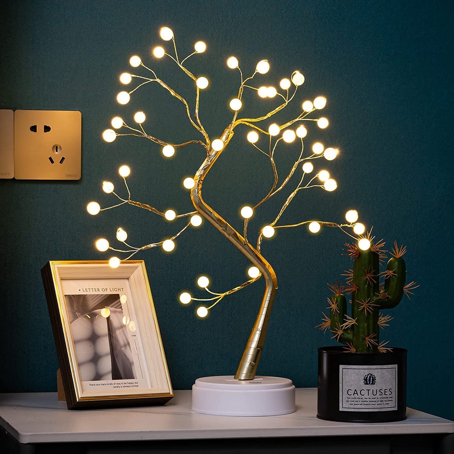 A lamp adorned with a tree pattern and a nearby green plant.