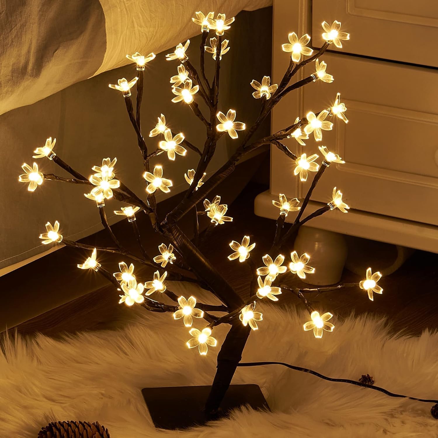 An indoor setting with a small tree decorated with lights.