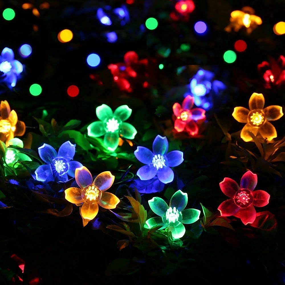 A vibrant arrangement of colorful flowers illuminated by soft, twinkling lights in a serene setting.