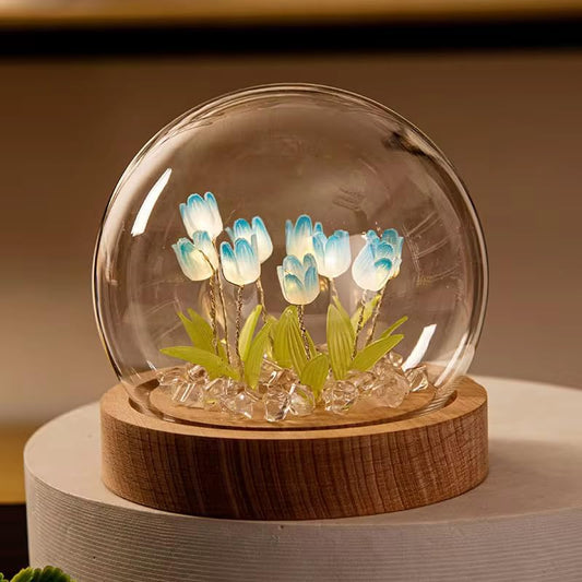 A glass globe containing delicate blue flowers, showcasing a serene and elegant floral arrangement within its transparent sphere.
