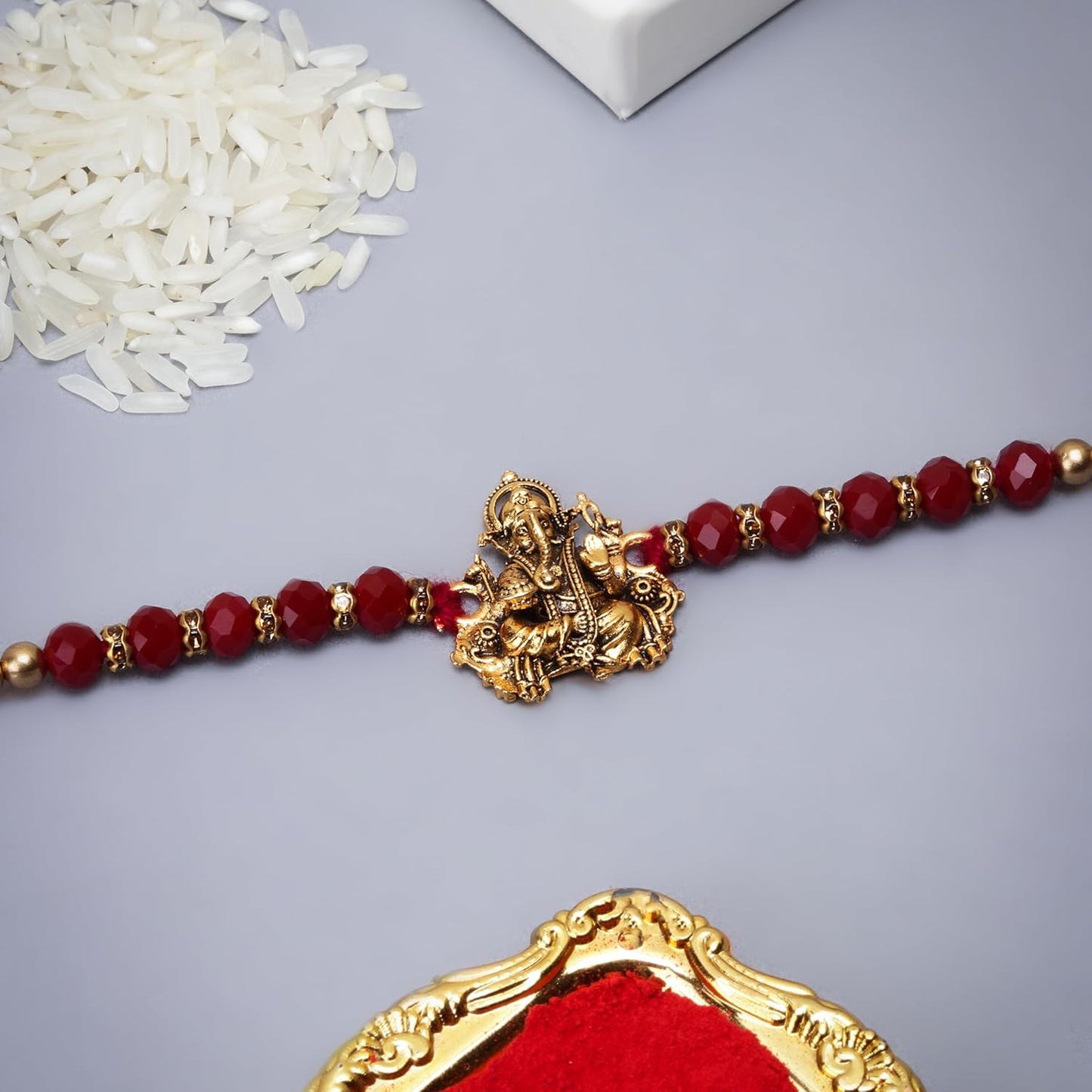 Stylish red bead Rakhi featuring a stunning gold and red stone, a chic accessory for any occasion.