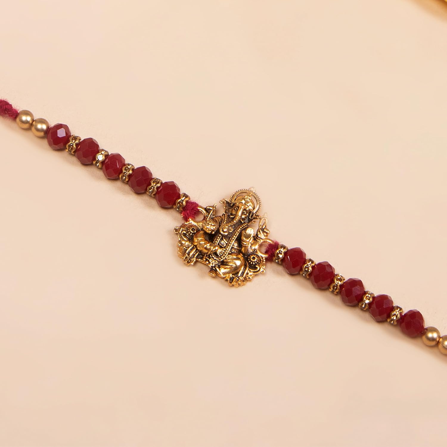 Add a touch of elegance to your look with this red bead Rakhi adorned with a beautiful gold and red stone.