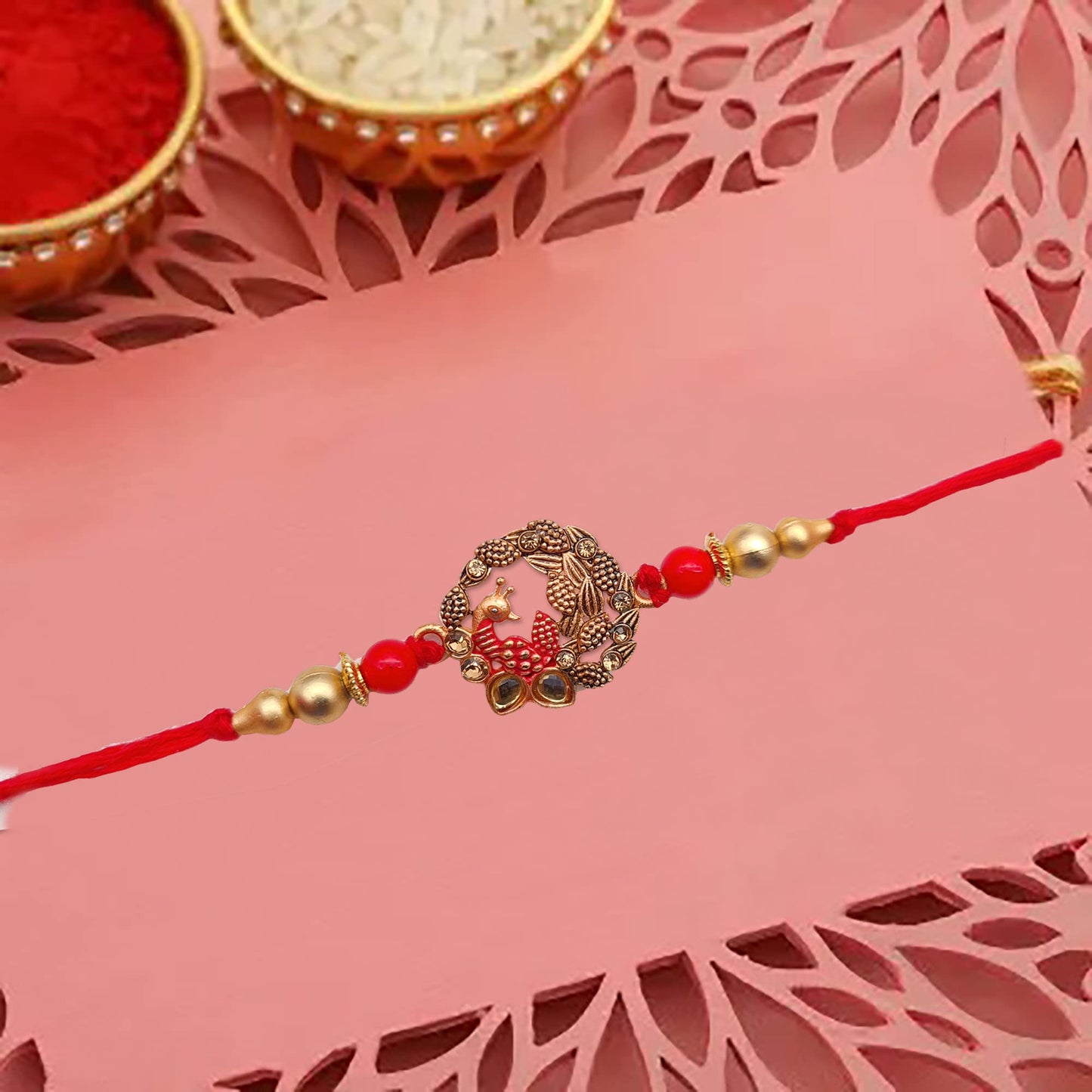 Red thread rakhi with gold bead.