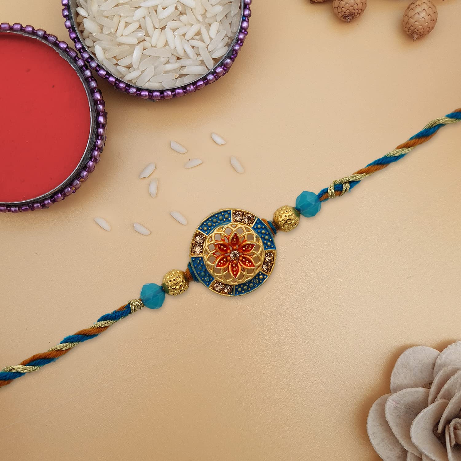 A gold and blue rakhi with a flower design, symbolizing love and protection.