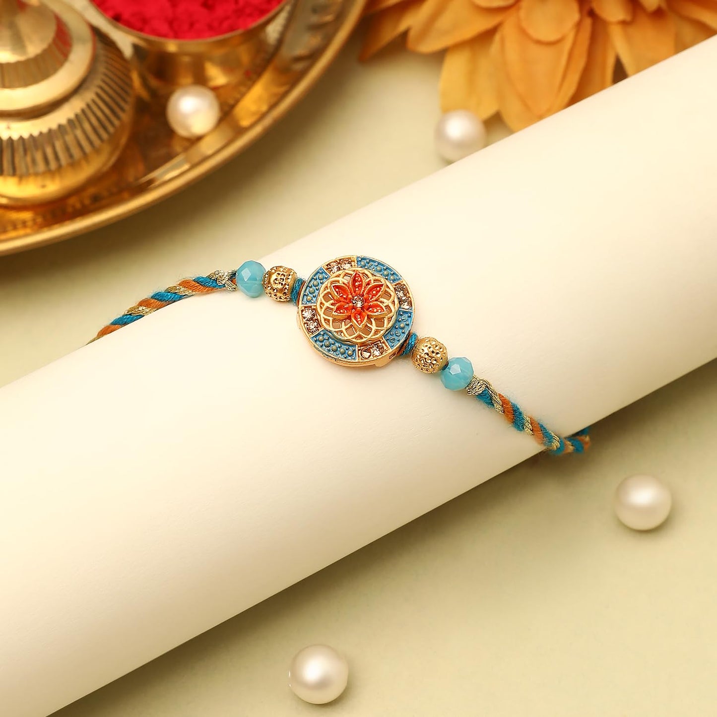 A gold and blue rakhi featuring a beautiful flower design, symbolizing the bond of love and protection between siblings.