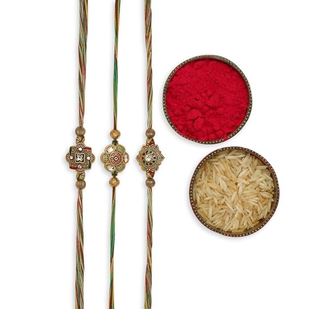 Three colorful rakhi's with a flower, vermilion, and a bowl of rice, symbolizing Raksha Bandhan festivities.