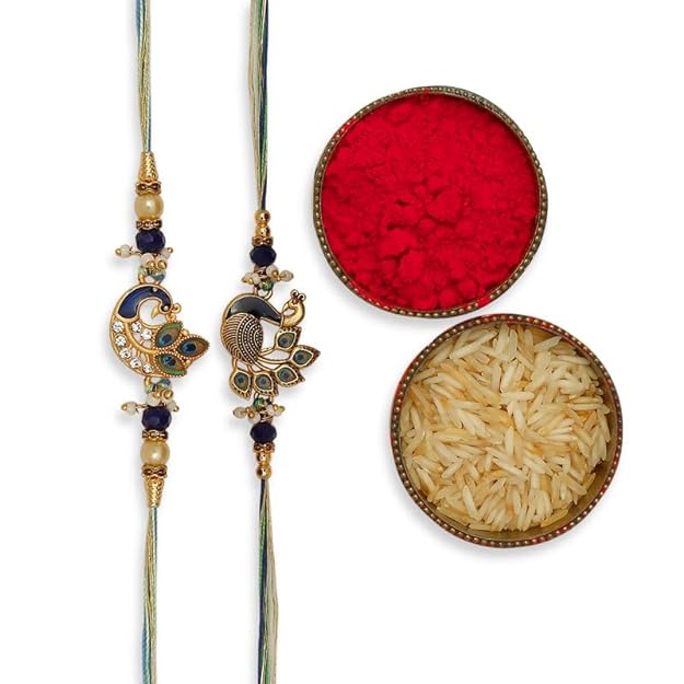 Two rakhi with peacock design and gold plated beads, surrounded by red powder and a bowl of rice.