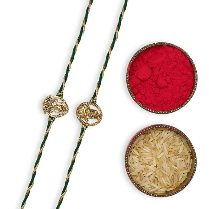 Two gold plated rakhi with green thread, red and gold design, gold chain, vermilion, rice bowl for Raksha Bandhan celebration.