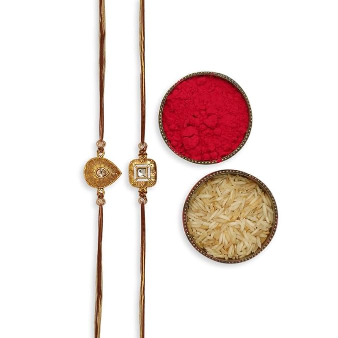 Two gold plated rakhi with heart and diamond, vermilion, and a bowl of rice, symbolizing Raksha Bandhan.