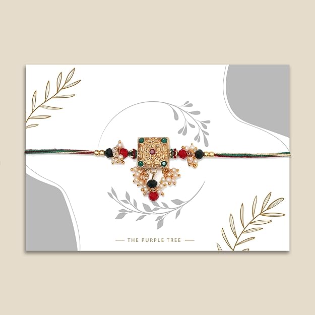  Intricately designed gold plated rakhi with green, red, and white beads, a symbol of the bond between siblings.