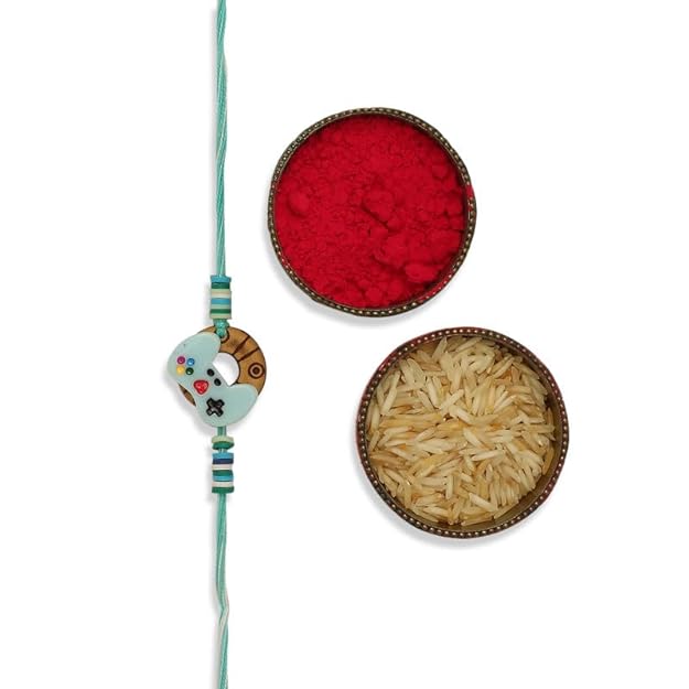 Beautifully  a blue and white Rakhi, red powder, and rice. 