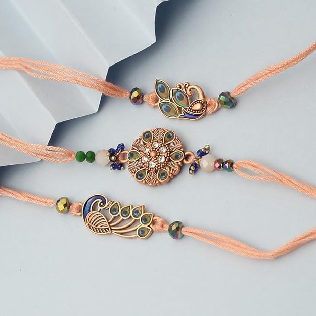 Three vibrant rakhi's in different colors, adorned with a flower and a majestic peacock.