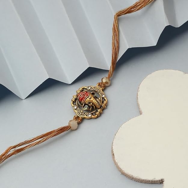 A beautiful gold and white rakhi with a cute little Ganpati charm. Perfect for celebrating the bond of love and protection.