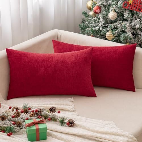  Two vibrant red pillows rest on a cozy couch beside a beautifully decorated Christmas tree.
