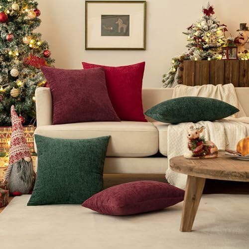 A cozy couch with two red pillows is positioned near a beautifully lit Christmas tree.