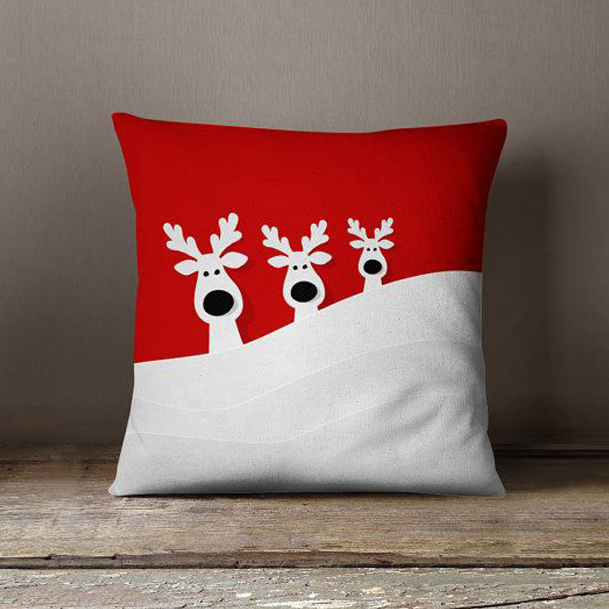 Three reindeers resting on a festive red and white pillow, creating a cozy and whimsical holiday scene.