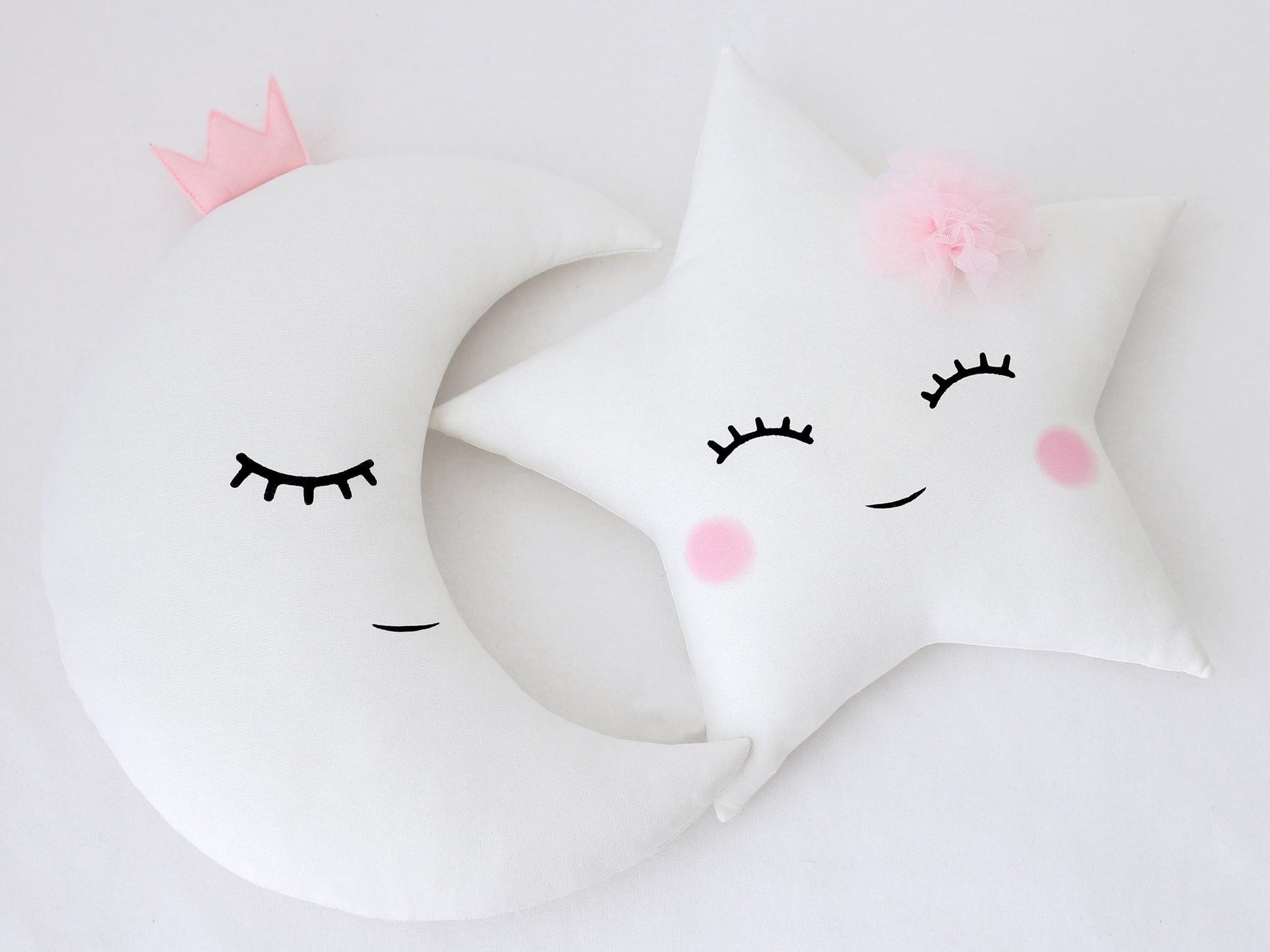 Three white pillows decorated with pink eyes