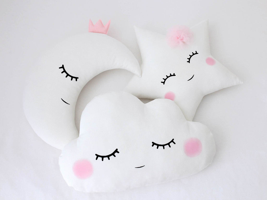 Three white pillows with pink eyes and a star moon and Cloud design.