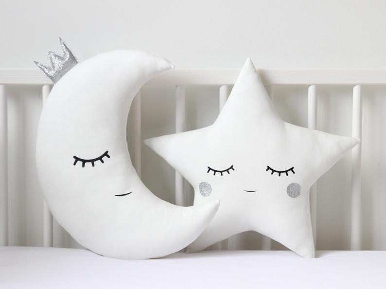 Spruce up your living space with these cute white pillows embellished with blue eyes and a star on top.