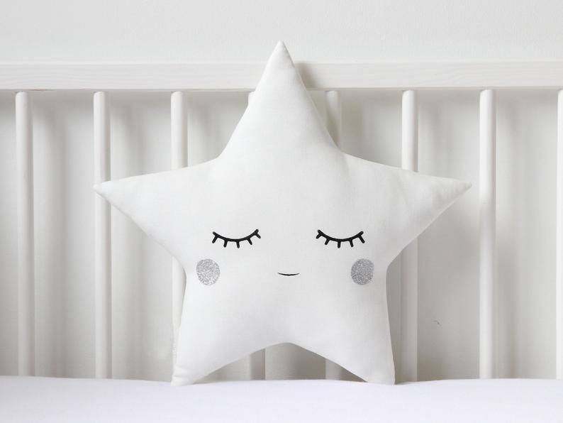 Add a playful touch to your room with these two white pillows featuring blue eyes and a star on top.