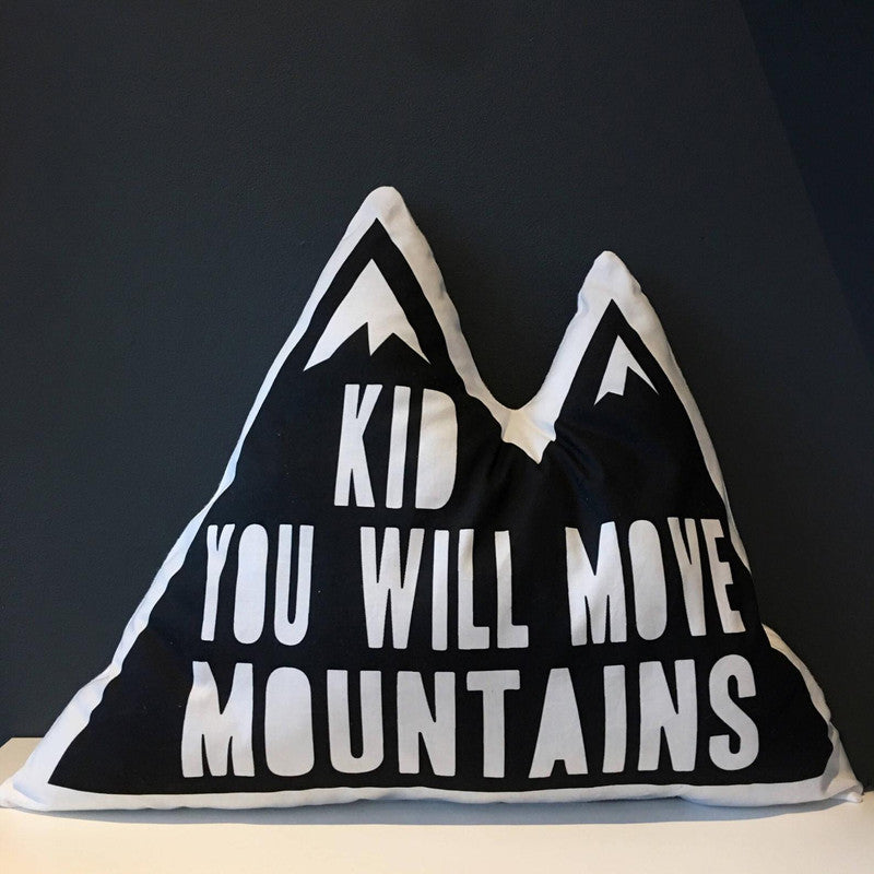 A motivational pillow with the quote "kid you will move mountains" embroidered on it.