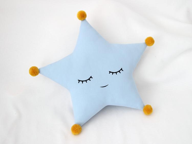 A cozy blue star pillow with adorable yellow eyes, perfect for snuggling and adding a touch of cuteness to any room.