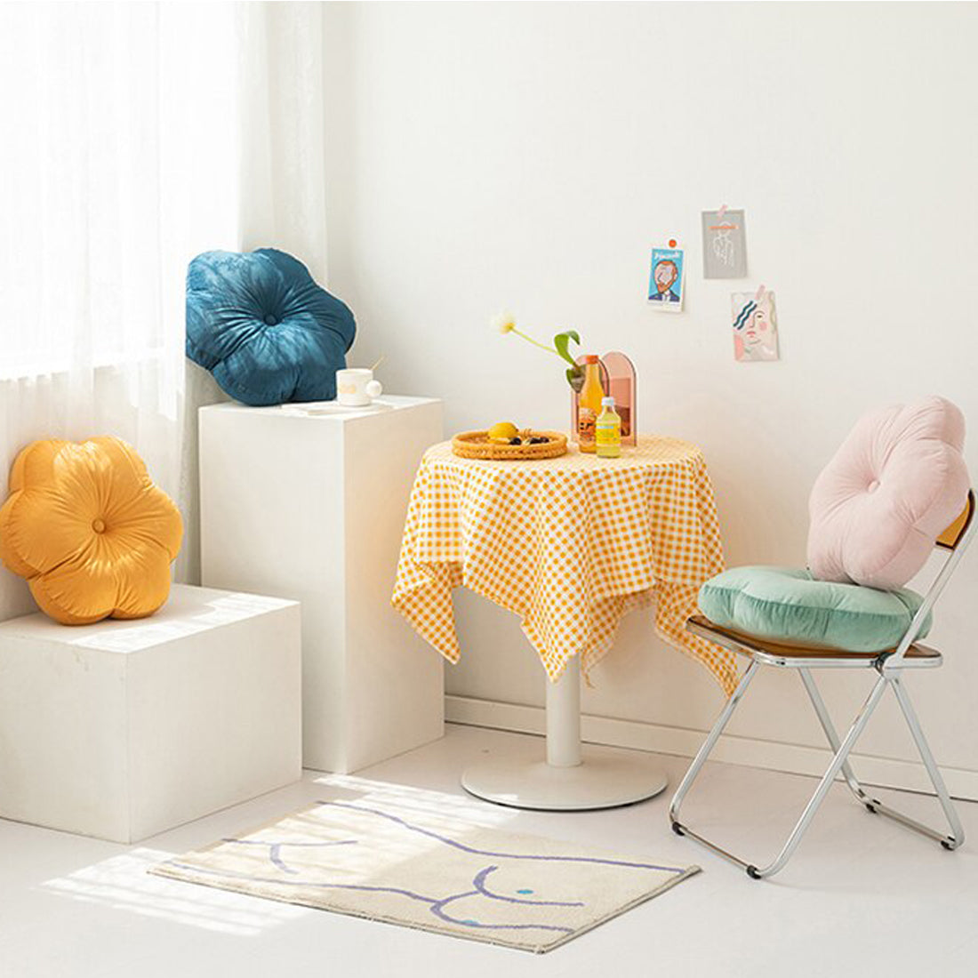 Pillows in stack on table next to yellow and blue checkered tablecloth.