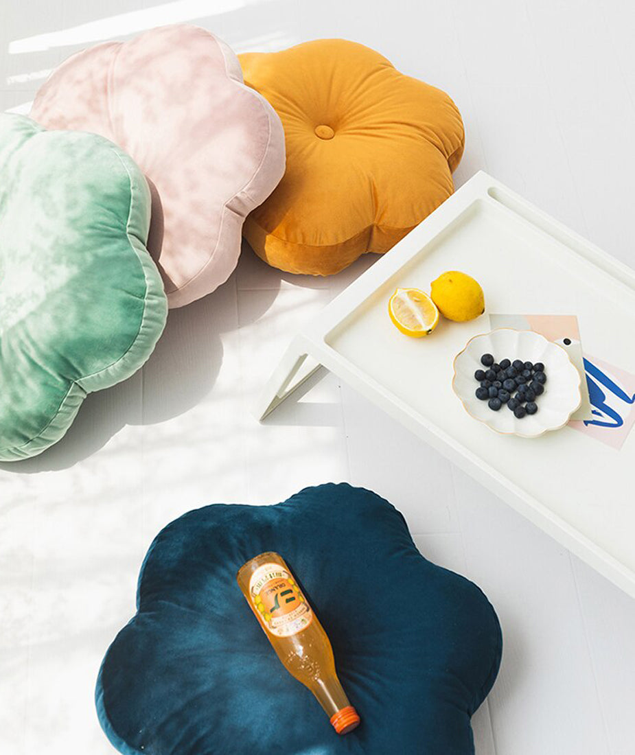  Bright yellow floral cushion resting on a clean white table surface.