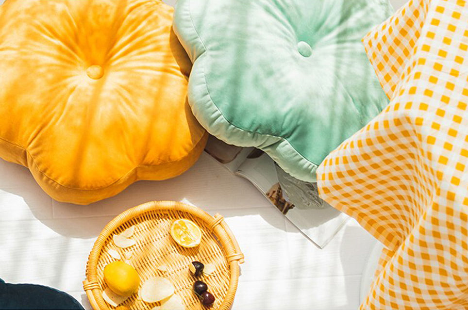 Pile of pillows on table near yellow and blue checkered tablecloth.