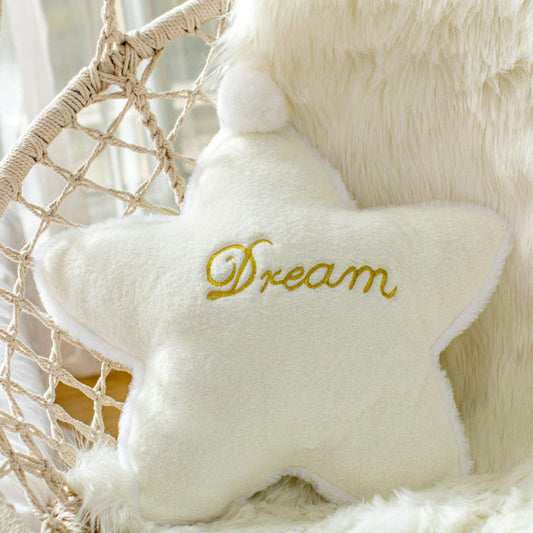 A white pillow with the word "dream" written on it, providing a cozy and inspirational touch to any bedroom decor.