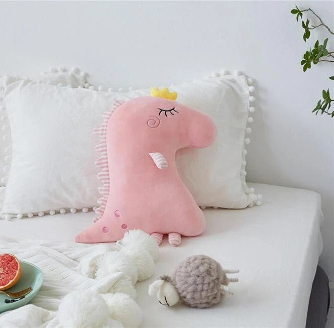 A plush toy wearing a crown rests on a bed, exuding a regal charm.