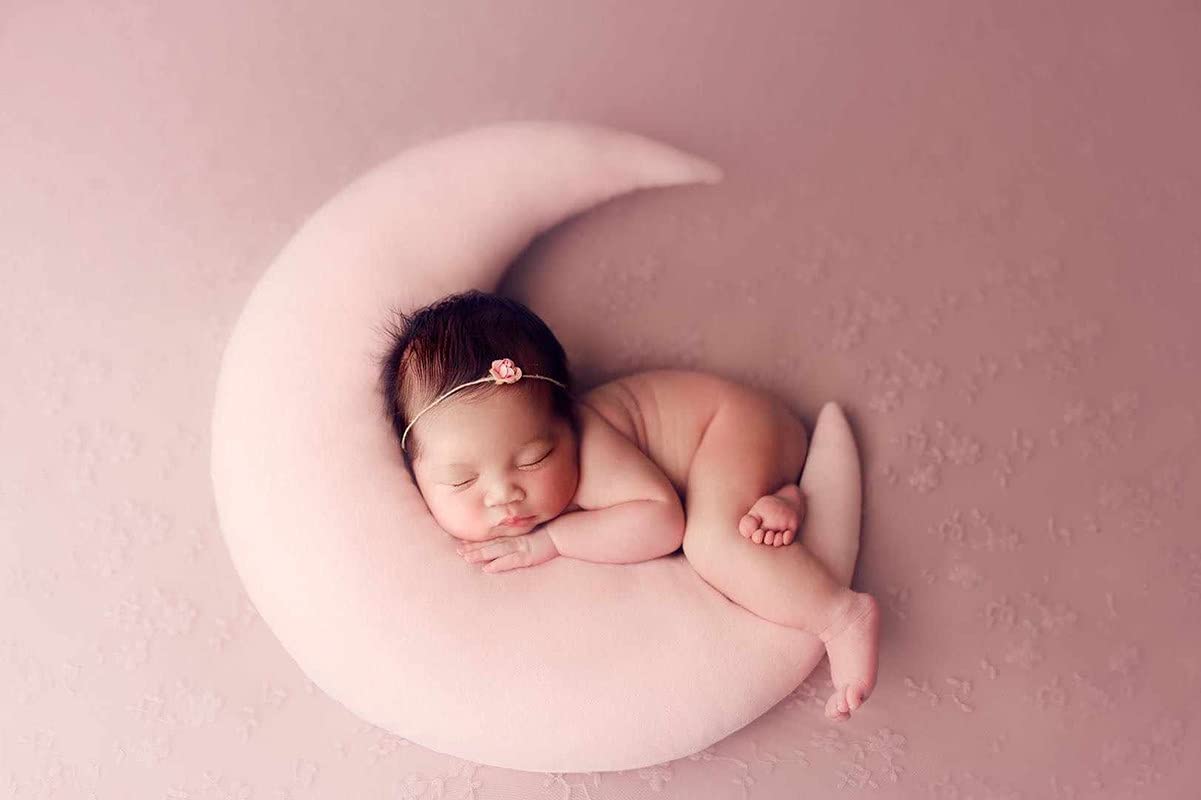 A peaceful baby girl sleeping on a crescent-shaped pillow adorned 