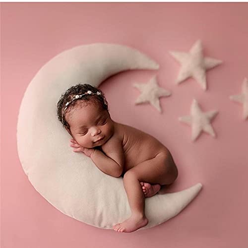 A peaceful baby girl sleeping on a crescent-shaped pillow adorned with stars.