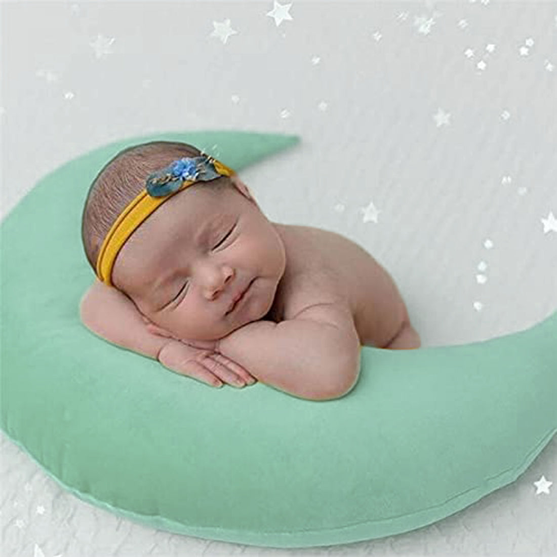 A peaceful baby girl sleeping on a green crescent-shaped pillow, enjoying a restful slumber.